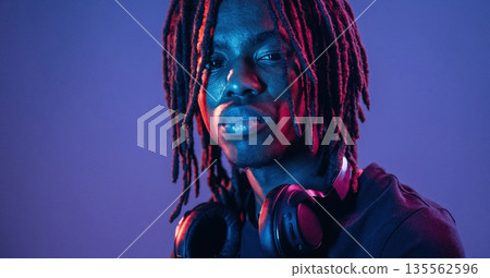 Dreadlocks hairstyle, portrait. African American guy is studio with neon lighting Dreadlocks hairstyle, portrait. African American guy is studio with neon lighting 135562596