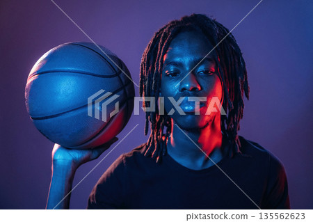 Red and blue lighting, holding ball. African American guy is studio Red and blue lighting, holding ball. African American guy is studio 135562623