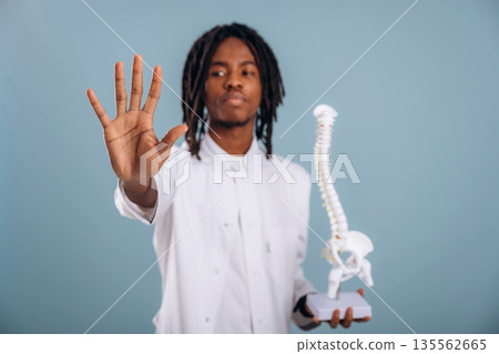 Education concept, human spine model. Black man is in the studio against soft background 135562665
