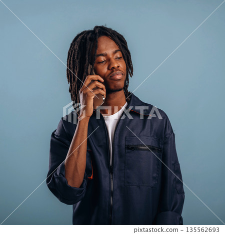 Talking by phone. Black man is in the studio against soft background Talking by phone. Black man is in the studio against soft background 135562693