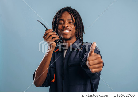 Using walkie talkie. Black man is in the studio against soft background Using walkie talkie. Black man is in the studio against soft background 135562700