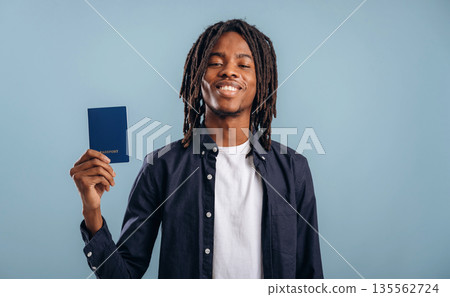 Tourist is with passport. Black man is in the studio against soft background Tourist is with passport. Black man is in the studio against soft background 135562724