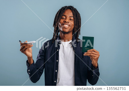 Vacation time, ready for travel. Black man is in the studio against soft background Vacation time, ready for travel. Black man is in the studio against soft background 135562731