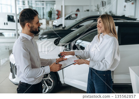 Man and woman are in the car dealership 135562857