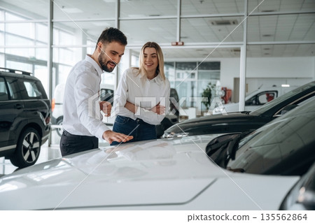 Man and woman are in the car dealership 135562864