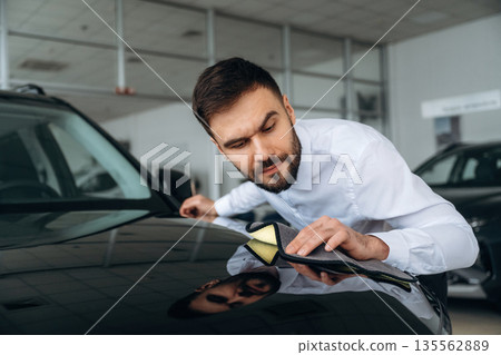 Checking the surface. Dealership worker is near the car Checking the surface. Dealership worker is near the car 135562889