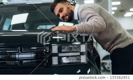 Polished surface. Man is with the car in dealership Polished surface. Man is with the car in dealership 135562951