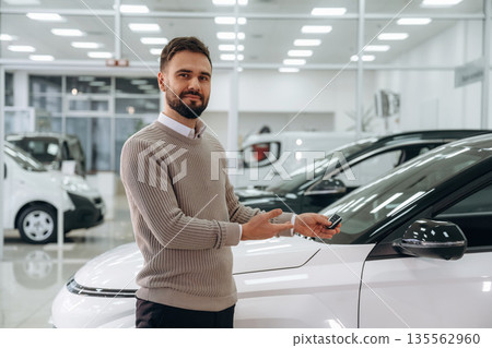 Keys for new automobile. Man is with the car in dealership Keys for new automobile. Man is with the car in dealership 135562960