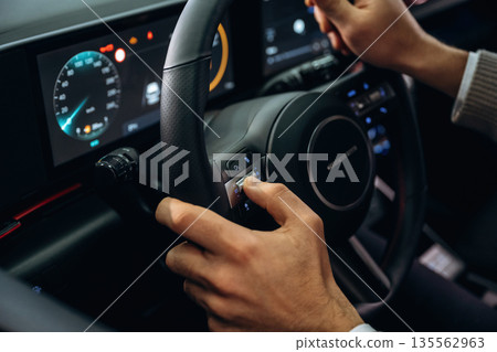 Driving, holding steering wheel. Man is sitting in car, detailed view Driving, holding steering wheel. Man is sitting in car, detailed view 135562963