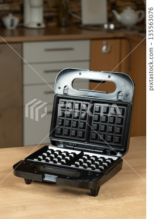 Electric Waffle Maker Appliance Ready for Use on a Wooden Kitchen Countertop. Electric Waffle Maker Appliance Ready for Use on a Wooden Kitchen Countertop. 135563076