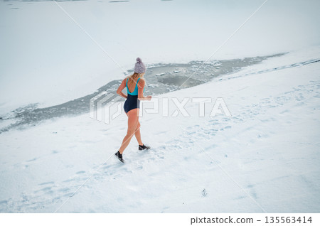 Elderly winter swimmer warming up before cold plunge in lake. 135563414