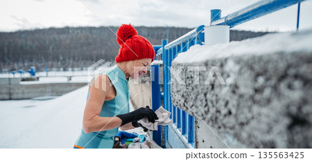 Senior woman preparing for winter swimming in an icy lake for health benefits. 135563425
