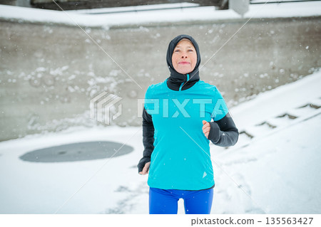 Winter workout for senior woman in snowy city. Winter workout for senior woman in snowy city. 135563427