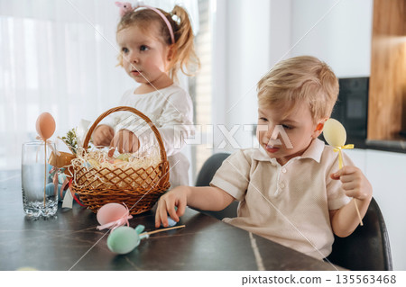 Holidays, colorful eggs for Easter. Kids are preparing bakery at home 135563468