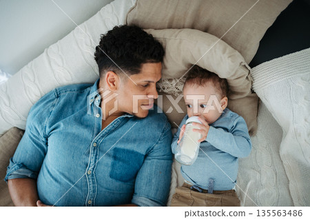 Father bottle feeding a small toddler son. Father bottle feeding a small toddler son. 135563486