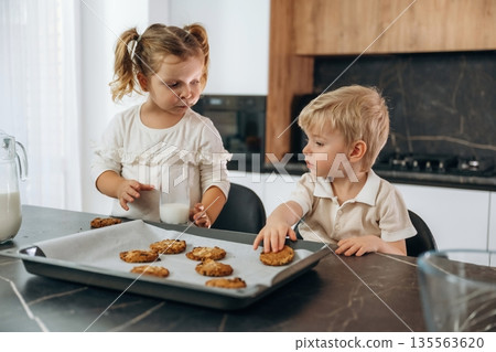 Eating cookies and drinking milk. Kids are preparing bakery at home Eating cookies and drinking milk. Kids are preparing bakery at home 135563620