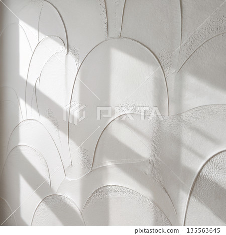 Decorative plaster wall pattern with soft sunlight shadows 135563645