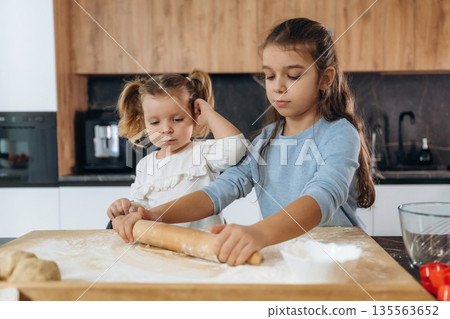 Dough work. Two little girls are preparing bakery at home Dough work. Two little girls are preparing bakery at home 135563652