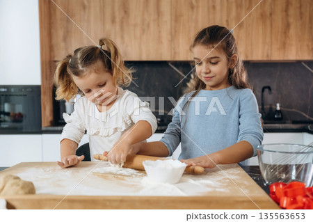 Dough work. Two little girls are preparing bakery at home Dough work. Two little girls are preparing bakery at home 135563653