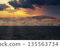 View of a coastal Eilat city at sunset with mountains in the background and dark clouds above sea 135563734