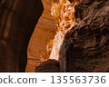 Exploring the canyon with sunlight shining on stone walls and cliffs. Petra, Jordan. 135563736