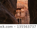 View of ancient structure in Petra surrounded by tall rock formations at sunset time 135563737