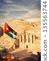 Exploring Petra in Jordan with a view of the Monastery and a national flag flying 135563744