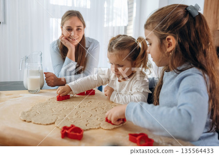 Preparing bakery. Mother with her little daughters at home 135564433