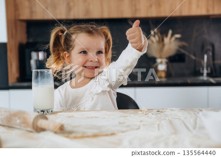 With milk in glass. Little girl is preparing bakery at home With milk in glass. Little girl is preparing bakery at home 135564440