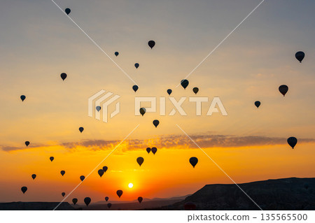 Hot air balloon flying over rocky landscape at sunrise in Cappadocia. Turkey Hot air balloon flying over rocky landscape at sunrise in Cappadocia. Turkey 135565500