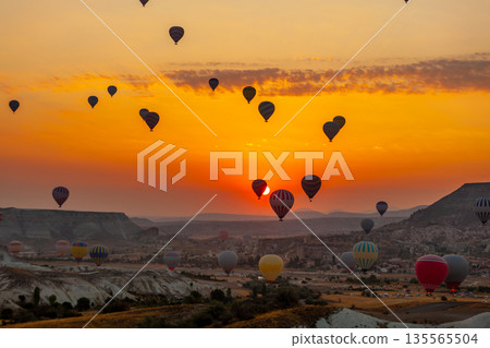 Hot air balloon flying over rocky landscape at sunrise in Cappadocia. Turkey Hot air balloon flying over rocky landscape at sunrise in Cappadocia. Turkey 135565504