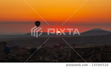 Hot air balloon flying over rocky landscape at sunrise in Cappadocia. Turkey Hot air balloon flying over rocky landscape at sunrise in Cappadocia. Turkey 135565510
