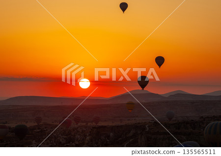 Hot air balloon flying over rocky landscape at sunrise in Cappadocia. Turkey Hot air balloon flying over rocky landscape at sunrise in Cappadocia. Turkey 135565511