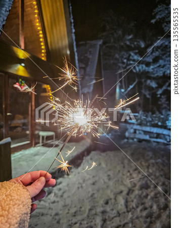 Hand Holding Sparkler Burning at Night Hand Holding Sparkler Burning at Night 135565535