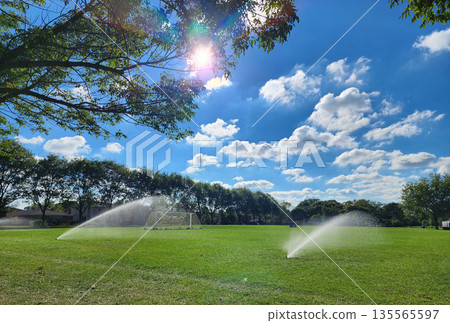 Sprinkler watering football field. System working football stadium. Automatic lawn sprinkler watering green grass. Water sprinklers watering soccer field. Football field. Irrigation of sport field Sprinkler watering football field. System working football stadium. Automatic lawn sprinkler watering green grass. Water sprinklers watering soccer field. Football field. Irrigation of sport field 135565597