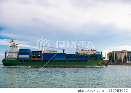 Container ship. Cargo ship with container. Freight container loaded on cargo vessel. View of cargo ship vessel navigating the sea leaving or entering harbor. Cargo business Container ship. Cargo ship with container. Freight container loaded on cargo vessel. View of cargo ship vessel navigating the sea leaving or entering harbor. Cargo business 135565652
