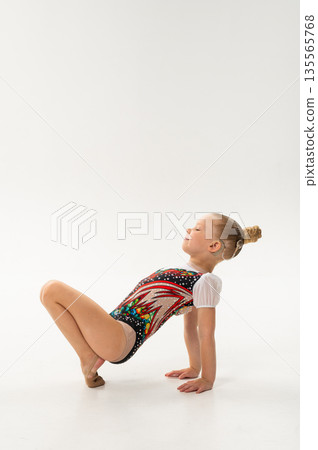 Young rhythmic gymnast with cochlear implant posing in training leotard in studio. Hearing rehabilitation, inclusive childhood sport and body awareness through flexibility and balance Young rhythmic gymnast with cochlear implant posing in training leotard in studio. Hearing rehabilitation, inclusive childhood sport and body awareness through flexibility and balance 135565768
