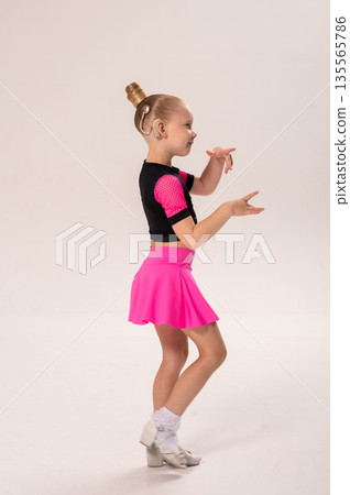 Little girl with hearing implant dancing in black and pink costume. Overcoming deafness with technology, creativity, and the expressive joy of inclusive childhood art. 135565786