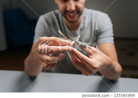 Man holding in hand and looking examining tangled dirty side brush from robot vacuum, illustrating maintenance, replacement and improved smart home cleaning efficiency and hygiene. Man holding in hand and looking examining tangled dirty side brush from robot vacuum, illustrating maintenance, replacement and improved smart home cleaning efficiency and hygiene. 135565999