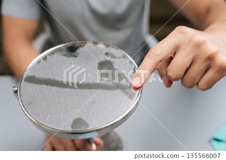 Close-up view of man cleaning dirty table mirror, creating clear streak with finger, illustrating need for hygiene and household chores. Concept of hygiene and cleanliness in domestic environment. 135566007
