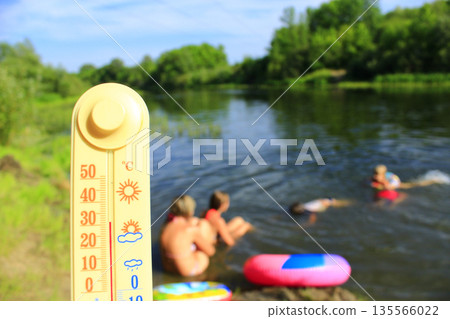 Thermometer with indication 31 degrees and bathing people in river. It is hot outside Thermometer with indication 31 degrees and bathing people in river. It is hot outside 135566022