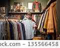 Mustachioed fashionable man customer on bargain hunting in second hand store for classy shirts. 135566458