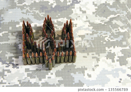 Coat of arms of Ukraine laid out from cartridges on camouflage clothing 135566789