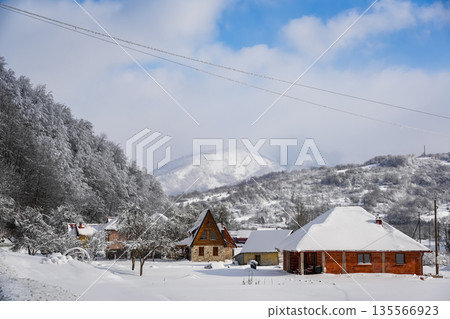 Snowy Cabins in Mountain Forest with Large Snow-Covered Peak Snowy Cabins in Mountain Forest with Large Snow-Covered Peak 135566923