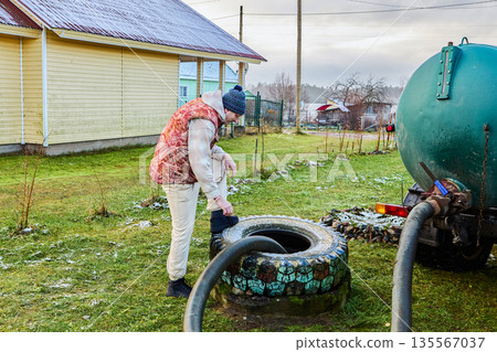Pumping sewage from septic tank using vacuum truck hose as worker controls suction process and ensures complete removal of liquid waste. 135567037