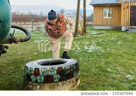 Sewage vacuum truck operation observed by sanitation worker inspecting circular cesspit opening before connecting hose for scheduled Honey sucker waste extraction. Sewage vacuum truck operation observed by sanitation worker inspecting circular cesspit opening before connecting hose for scheduled Honey sucker waste extraction. 135567044