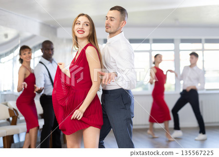 Group of young active people practicing vogue dancing movements while training twist or charleston in dance hall Group of young active people practicing vogue dancing movements while training twist or charleston in dance hall 135567225