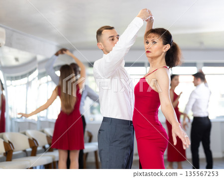 Young man and woman dancing waltz in couple during lesson at studio Young man and woman dancing waltz in couple during lesson at studio 135567253