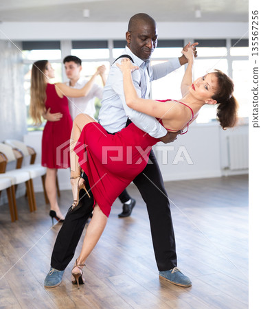 African man and woman dancing tango in couple during lesson at studio 135567256