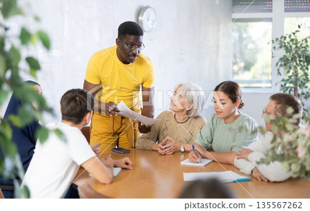 Group of multinational people discussing documents at table Group of multinational people discussing documents at table 135567262